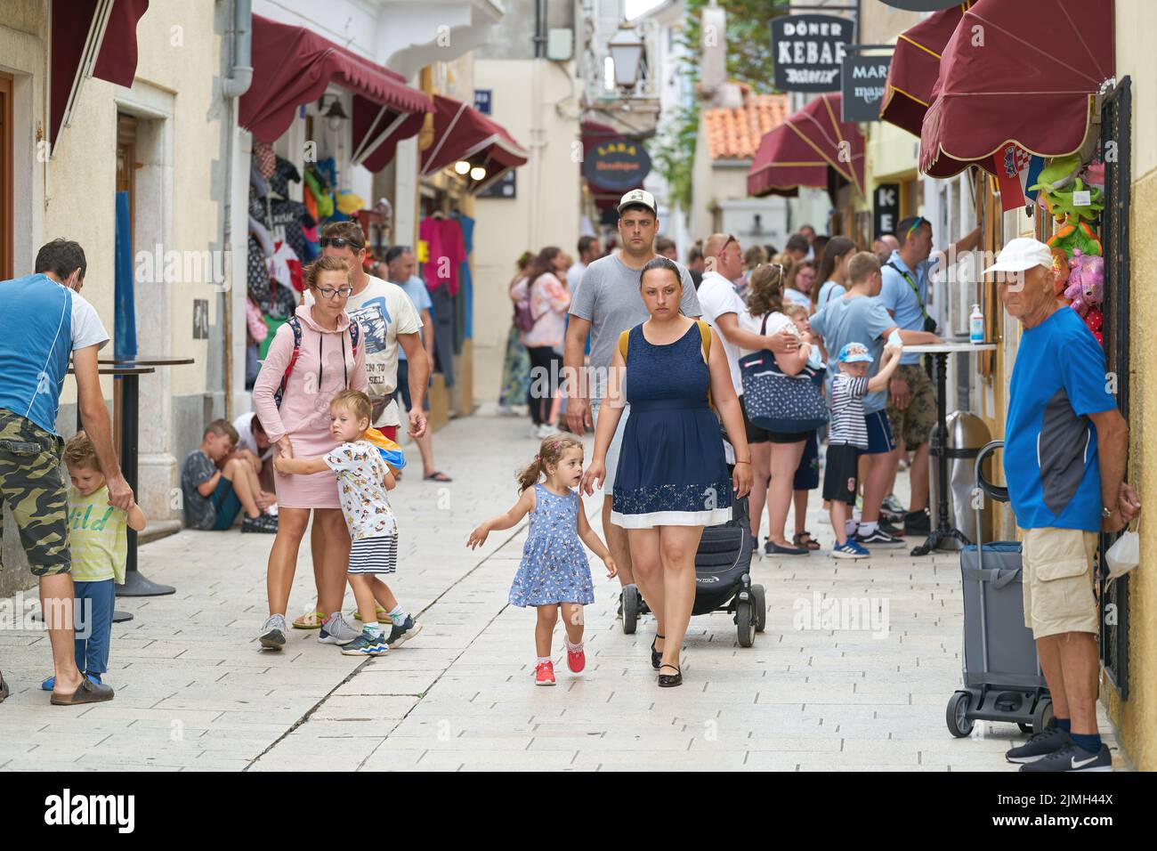 Touristes dans une allée avec des magasins dans la vieille ville de Krk en Croatie Banque D'Images