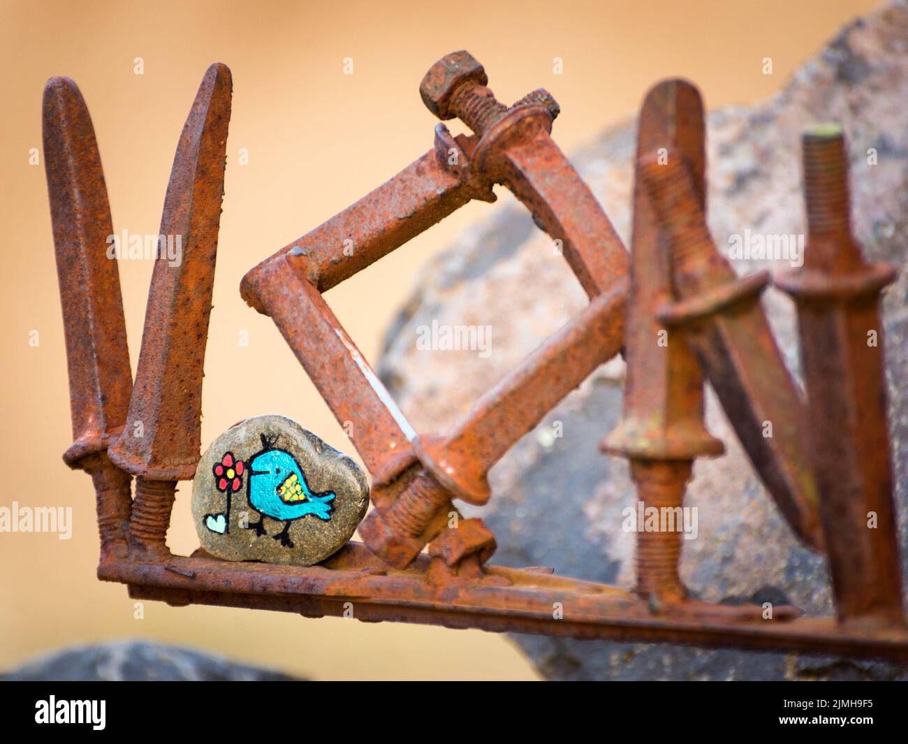 Peinture d'oiseau sur une petite pierre entre les pieux de metall Banque D'Images