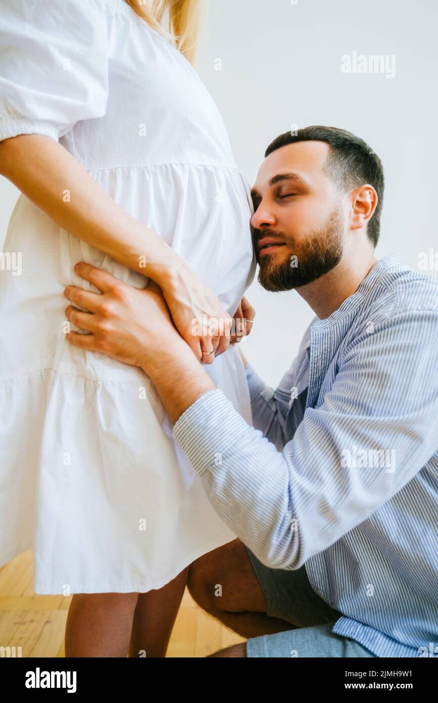 La future mère et le père ont classé la grossesse de gros ventre. Le mari embrasse la femme