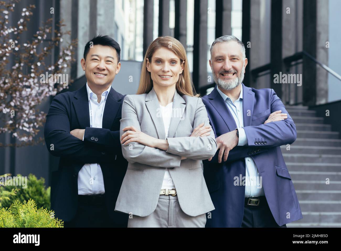 Femme patron d'affaires et son équipe diversifiée, asiatique homme regardant la caméra avec les bras croisés et souriant, équipe de rêve à l'extérieur du bâtiment de bureau Banque D'Images