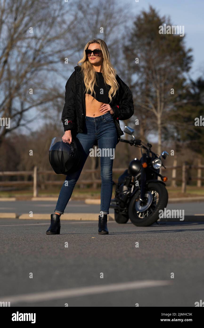 Un beau modèle Blonde apprécie le temps en extérieur en posant avec sa moto Banque D'Images