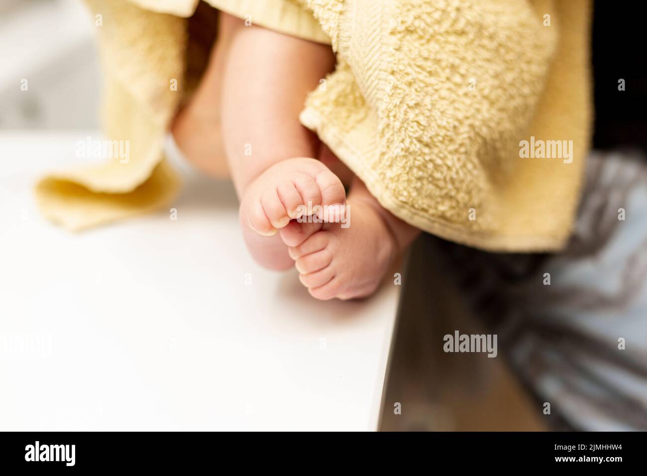 Fermez les jambes de bébé avec une serviette jaune Banque D'Images