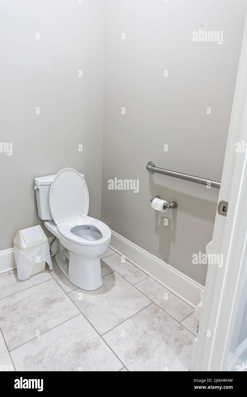Une petite salle de bains avec des murs gris et une toilette avec sol carrelé dans une nouvelle maison de construction avec une rambarde pour handicapés Banque D'Images