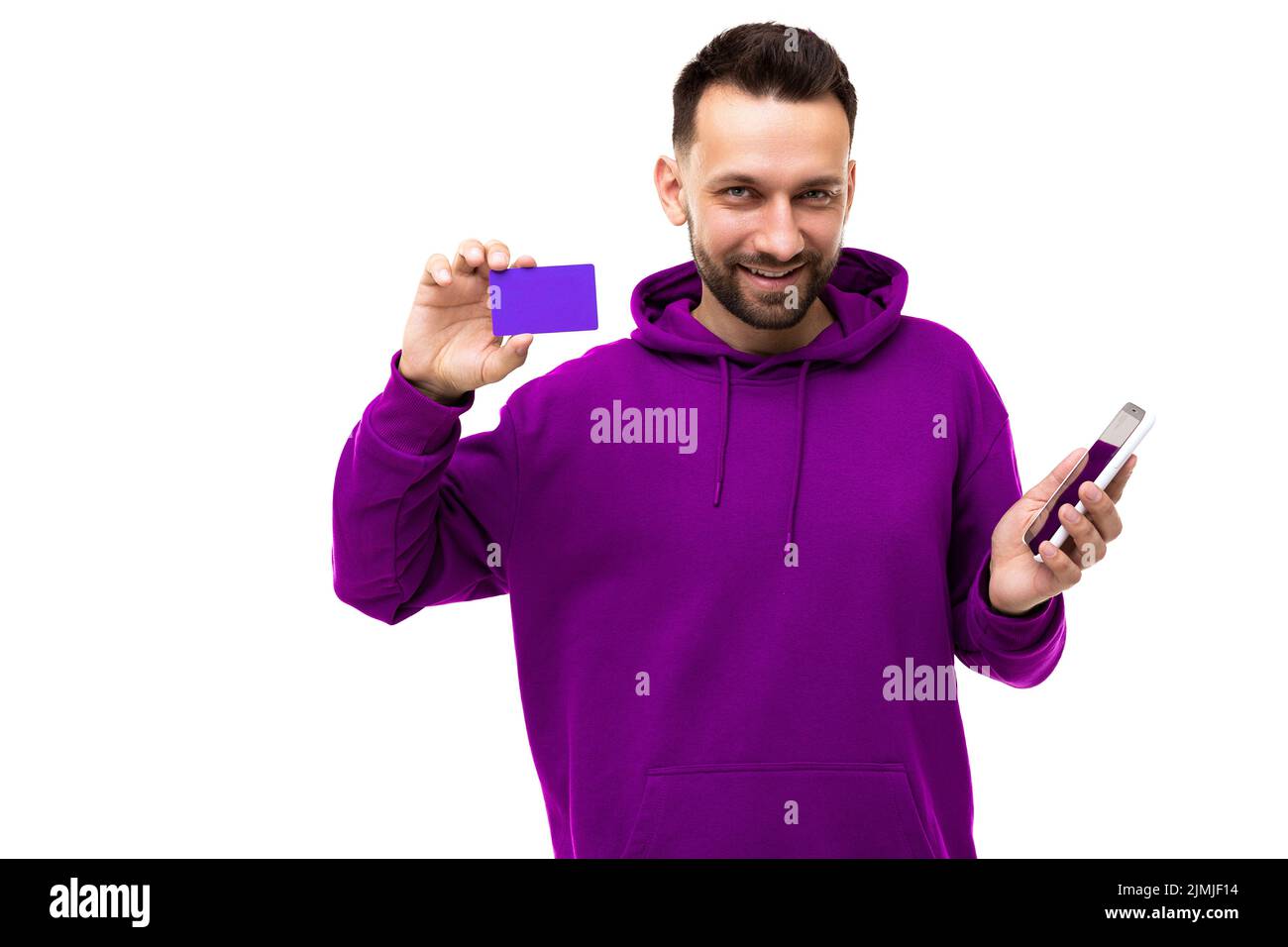 Cet homme d'âge moyen à la coupe très tendance présente une carte bancaire et une application sur laquelle il est possible de porter une barbe avec un sweat-shirt violet Banque D'Images