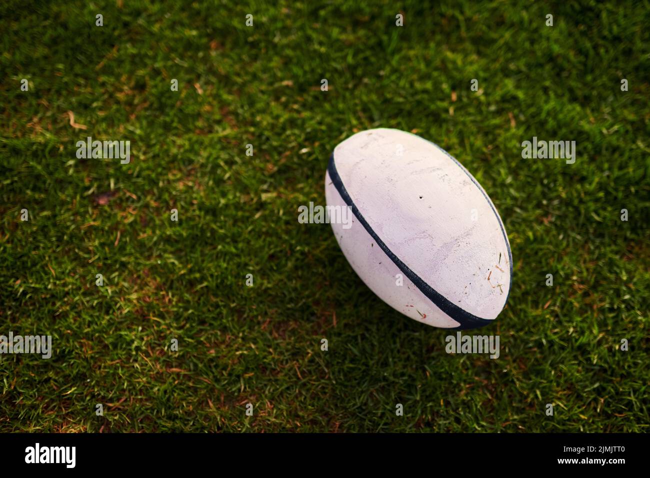 Que les matchs commencent. Un ballon de rugby sur un terrain de rugby vide pendant les premières heures du matin. Banque D'Images