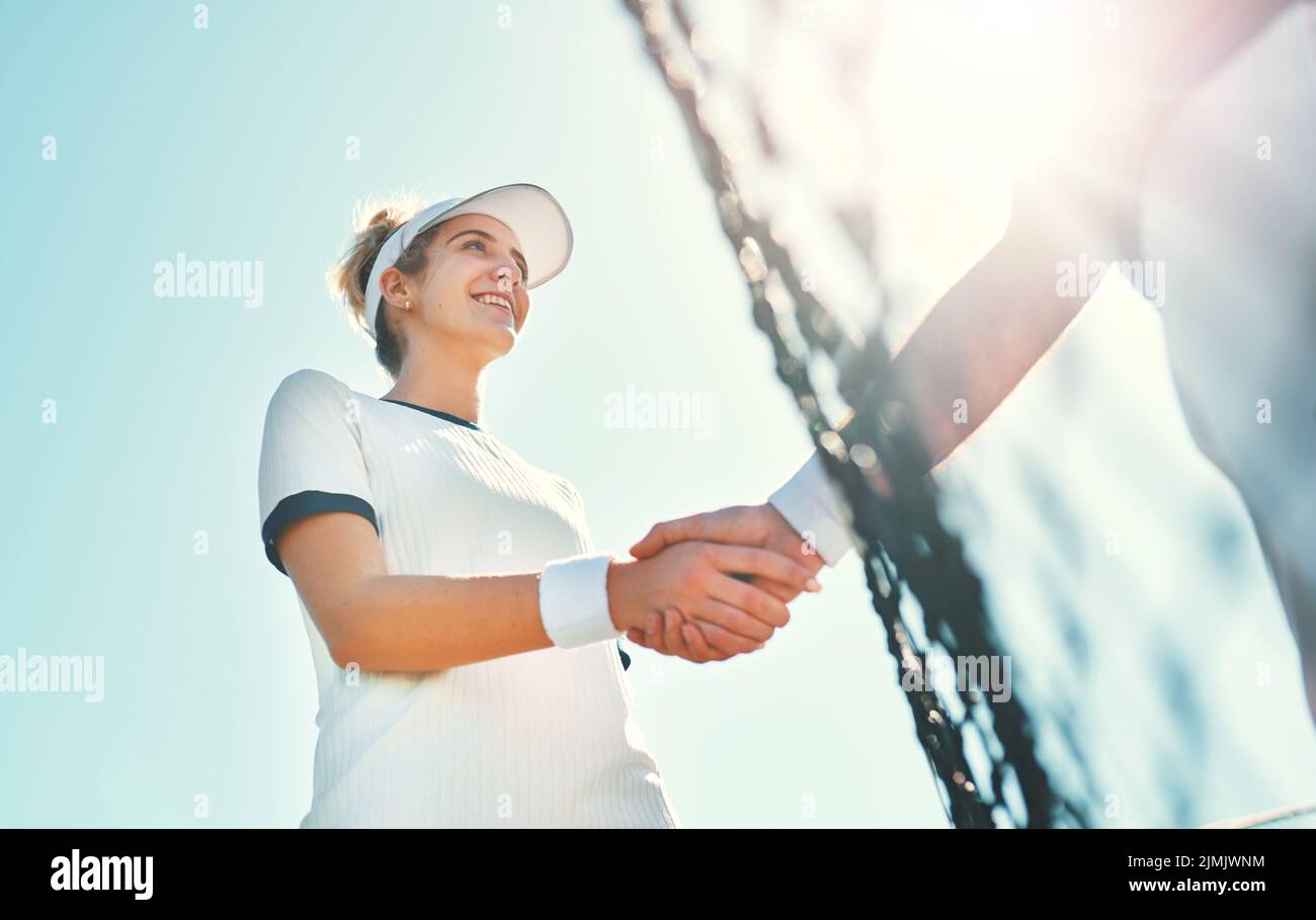 Soyez gracieuse dans vos victoires et vos défaites. Une jeune joueuse de tennis féminine attirante se serrant la main avec un adversaire en plein air sur le court. Banque D'Images