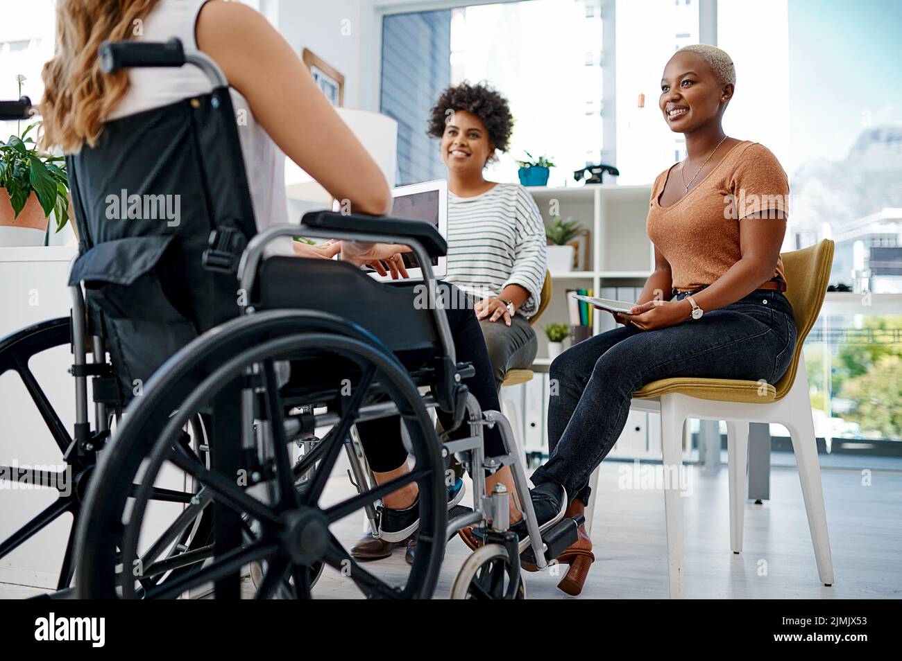 Ils travaillent dur pour développer leur marque. Une femme d'affaires handicapée assise avec des collègues au bureau. Banque D'Images