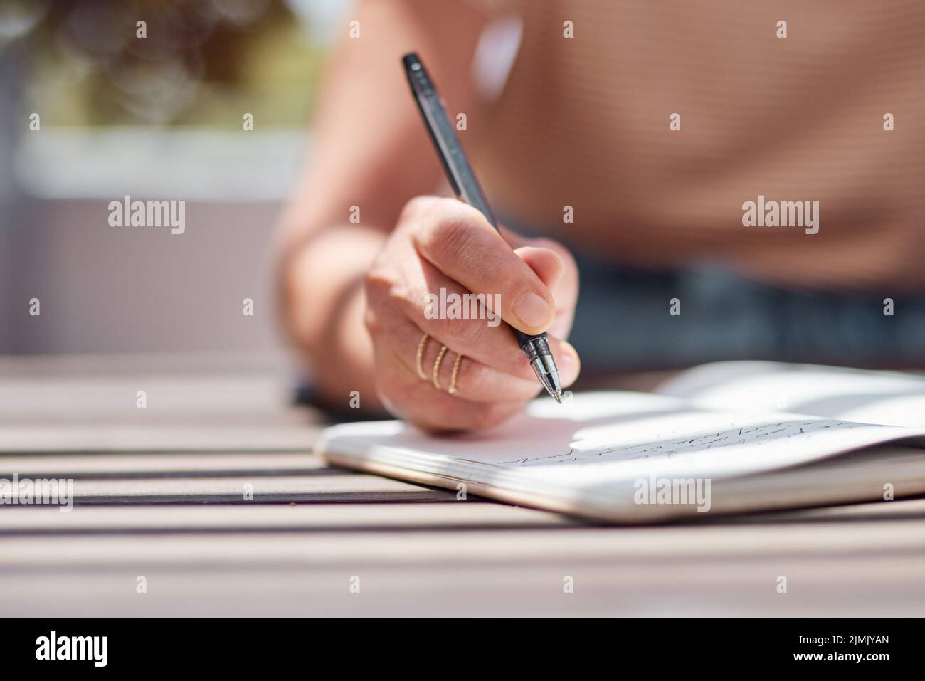 Son histoire fera l'histoire. Une femme méconnaissable écrivant dans un carnet sur le balcon à la maison. Banque D'Images