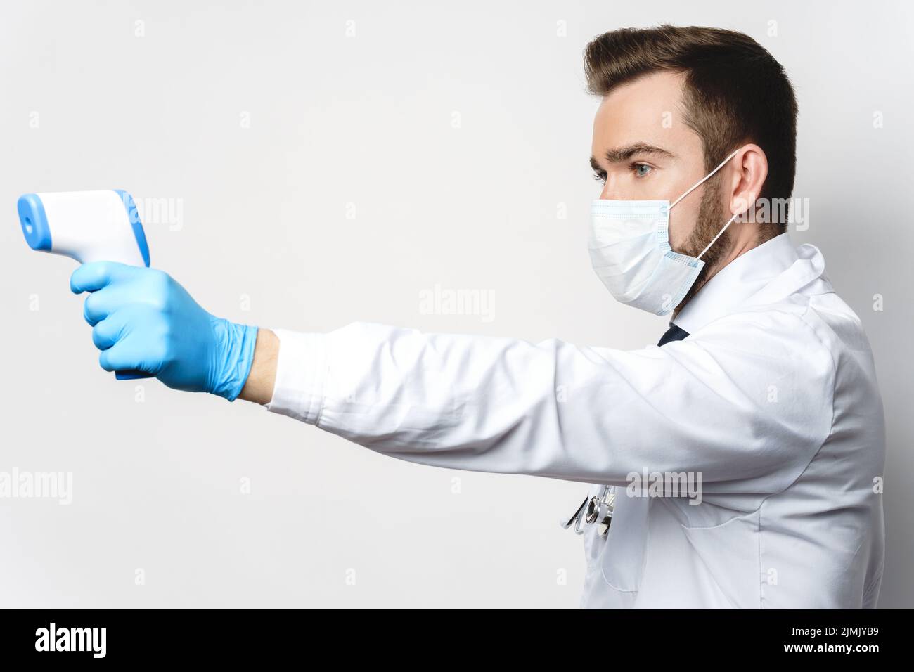 Le médecin mesure la température corporelle à l'aide d'un thermomètre infrarouge Banque D'Images