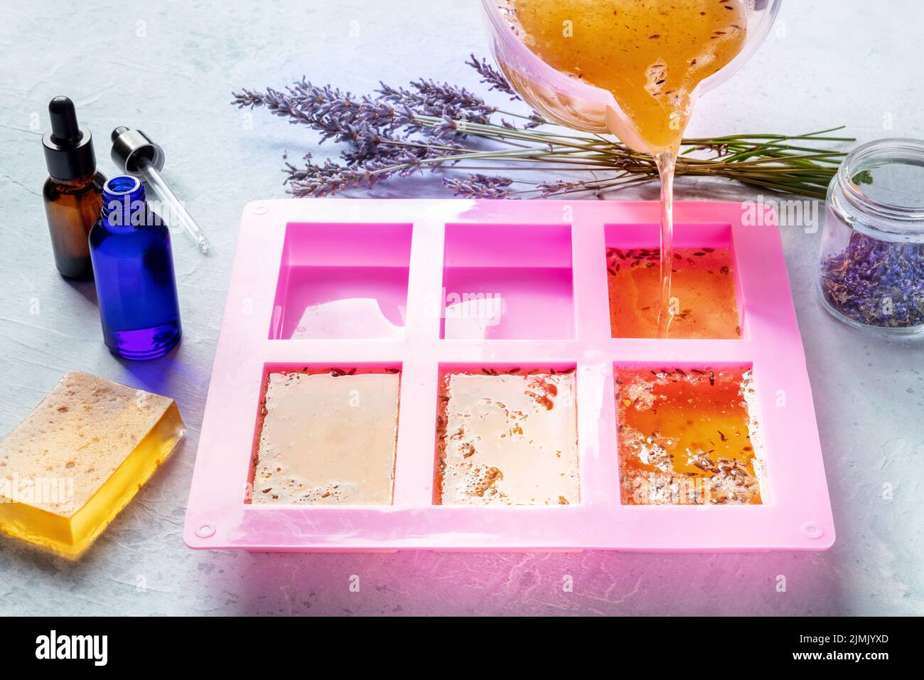 Fabrication de savon à la maison. La glycérine liquide avec les additifs  des peaux et des boutons de fleurs est versée dans un moule, avec des  huiles essentielles Photo Stock - Alamy