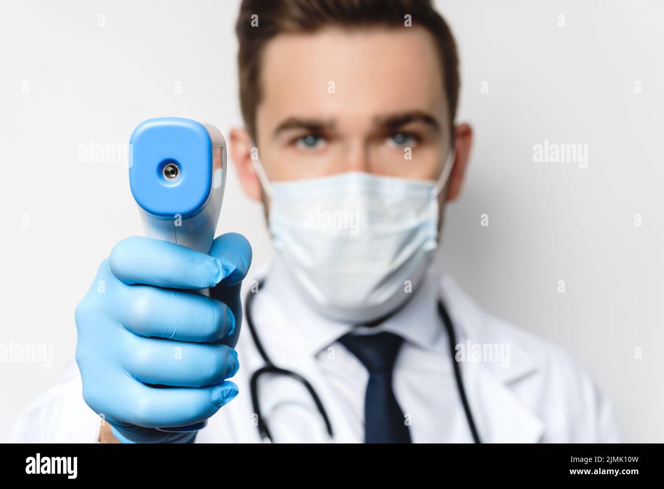 Le médecin mesure la température corporelle à l'aide d'un thermomètre infrarouge Banque D'Images