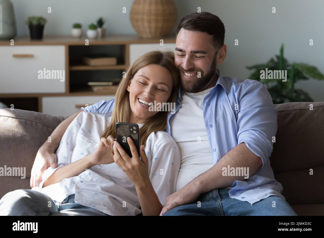 Les jeunes couples qui utilisent les informations de navigation sur smartphone passent leurs loisirs à la maison Banque D'Images