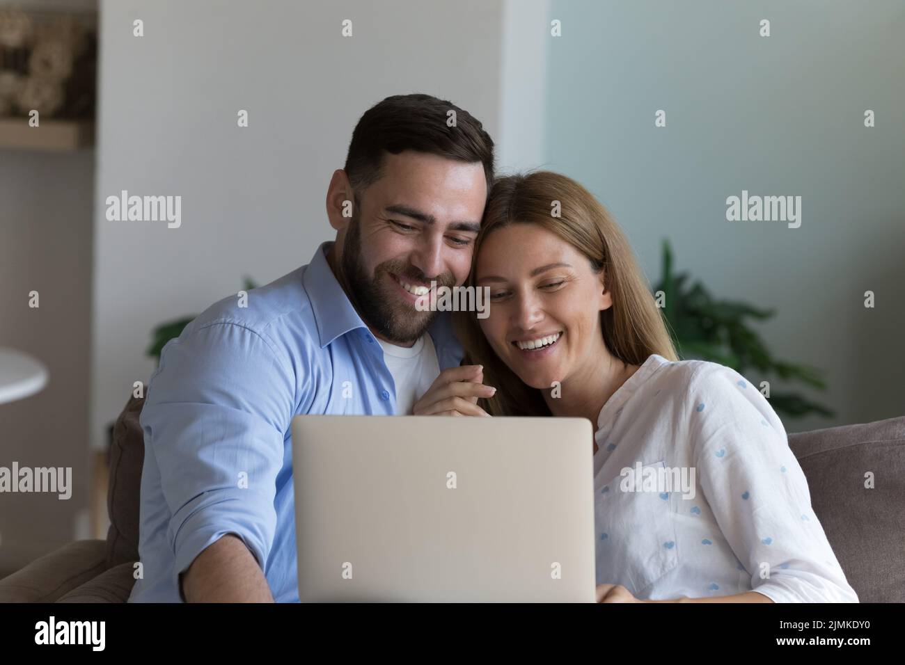 Beau couple regardant un film en ligne sur un ordinateur portable se relaxant sur un canapé Banque D'Images