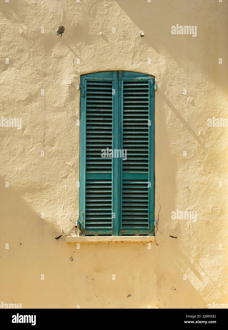 Vieux volets de fenêtre en bois fermés contre le mur jaune. Banque D'Images