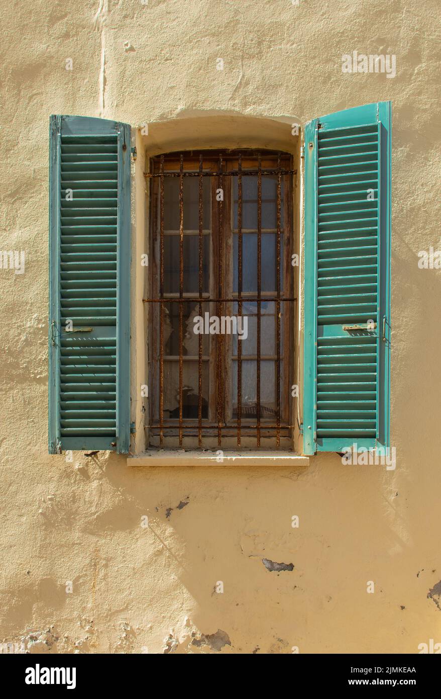 Ancienne fenêtre avec volets en bois et calandre rouillée. Banque D'Images