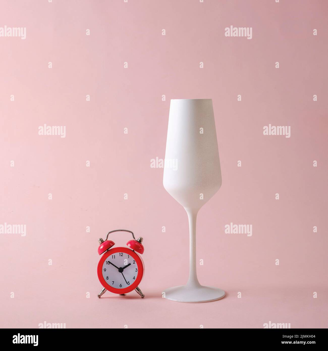 Réveil rétro et verre de champagne blanc sur fond pastel. Concept de vin créatif minimal. Banque D'Images