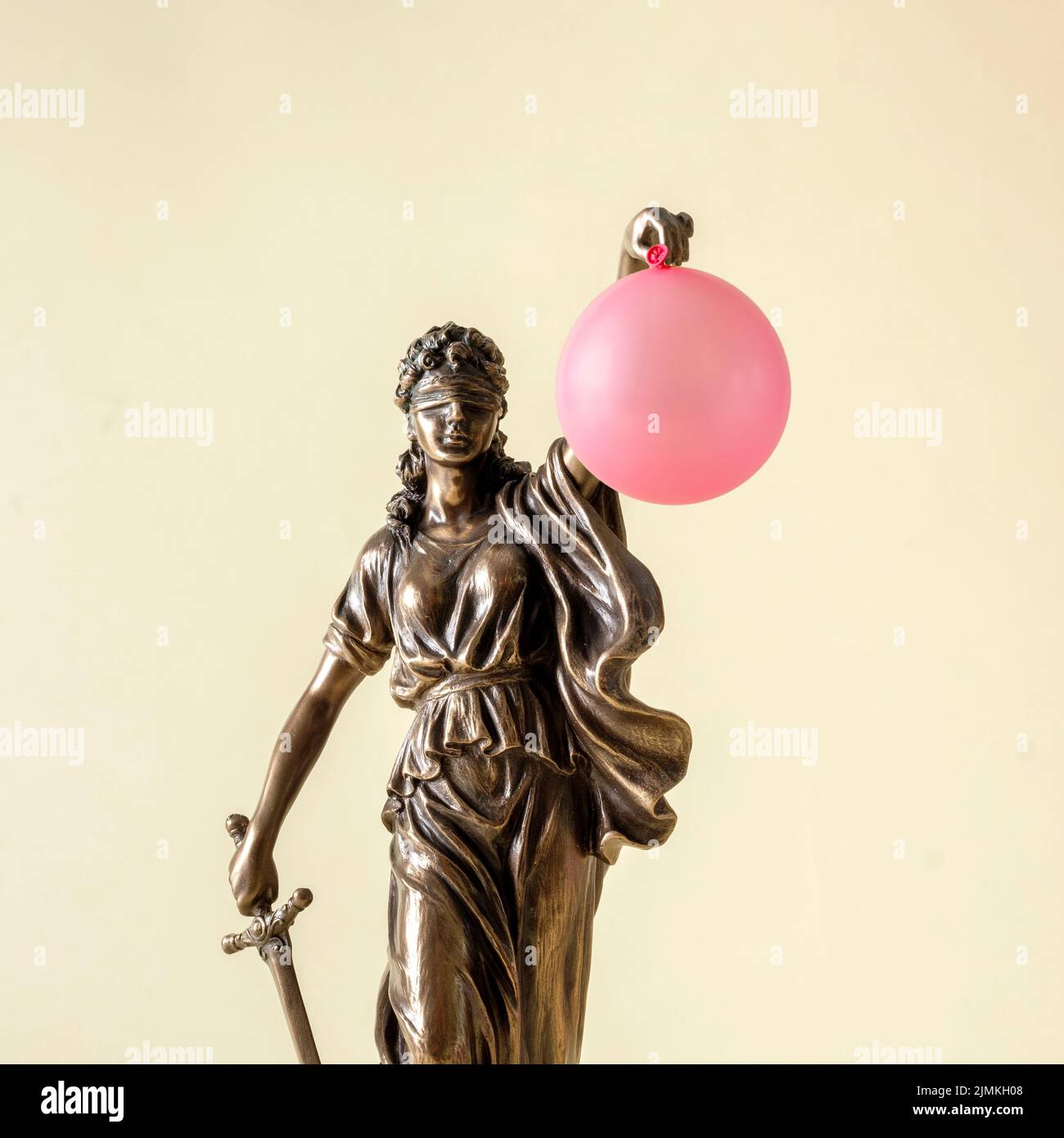Statue de justice et de droit Themis sur fond jaune pastel avec ballon rose. Une petite blague surprise et un cadeau inattendu. Banque D'Images