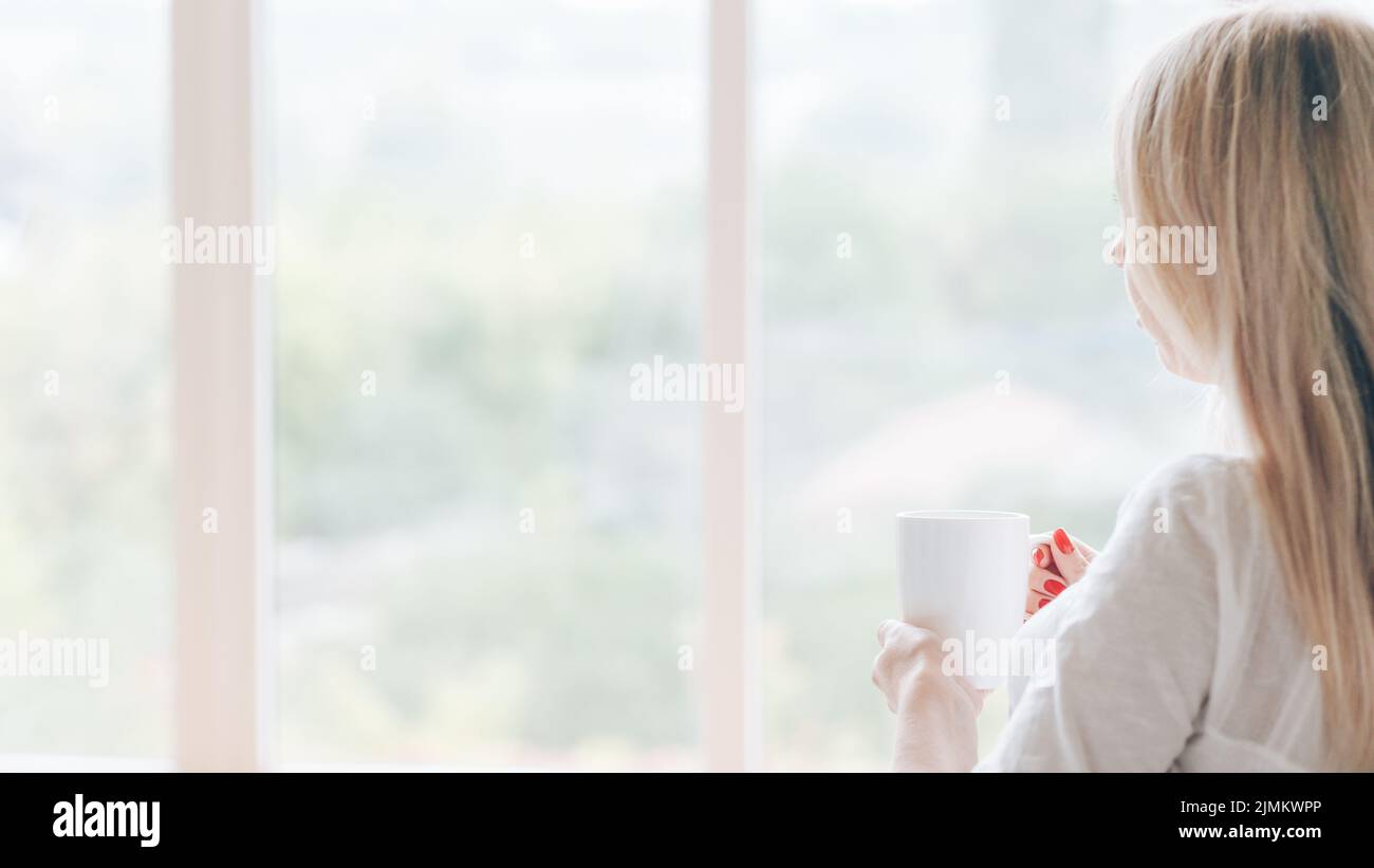 café du matin femme pensive fenêtre mug boisson chaude Banque D'Images