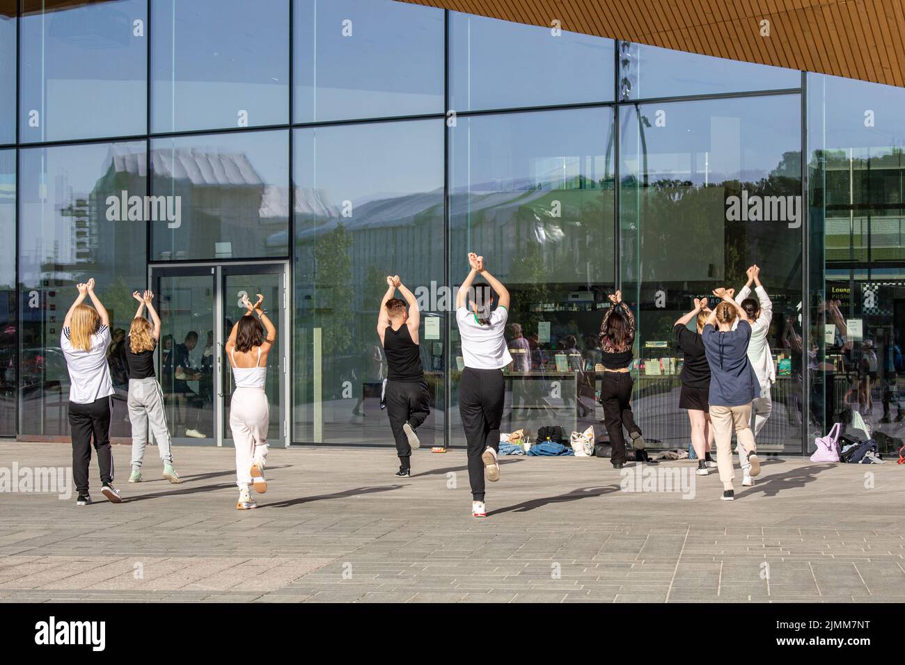 Jeunes adultes ou adolescents pratiquant des mouvements de danse devant la bibliothèque Oodi à Helsinki, en Finlande Banque D'Images