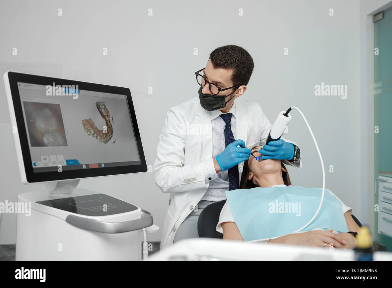 Patient en orthodontie masculin avec scanner intra-buccal et commandes à l'écran. Prosthodontie et stomatologie concept. Banque D'Images