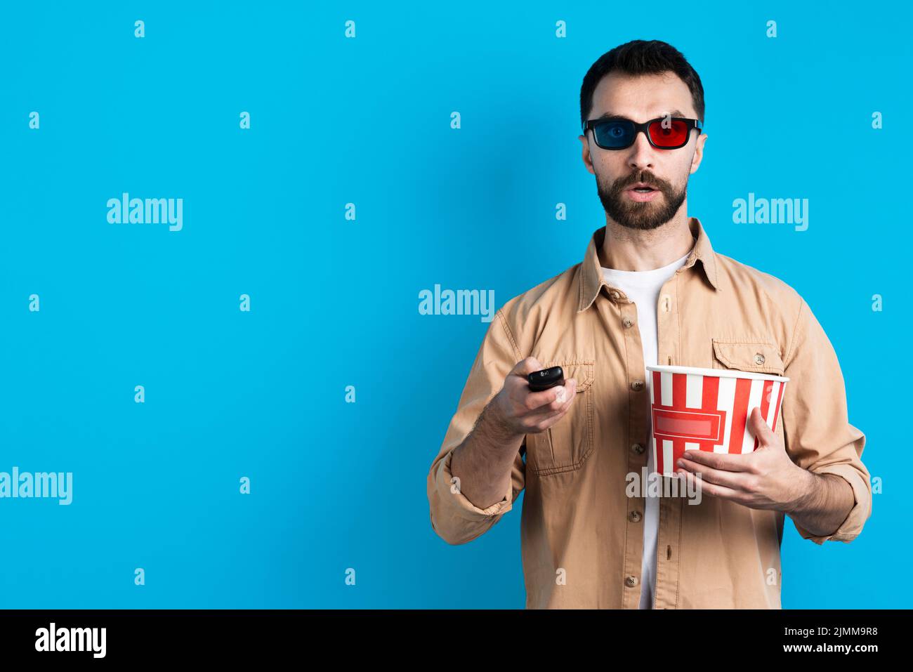 Homme avec des lunettes de cinéma pointant vers la télécommande Banque D'Images