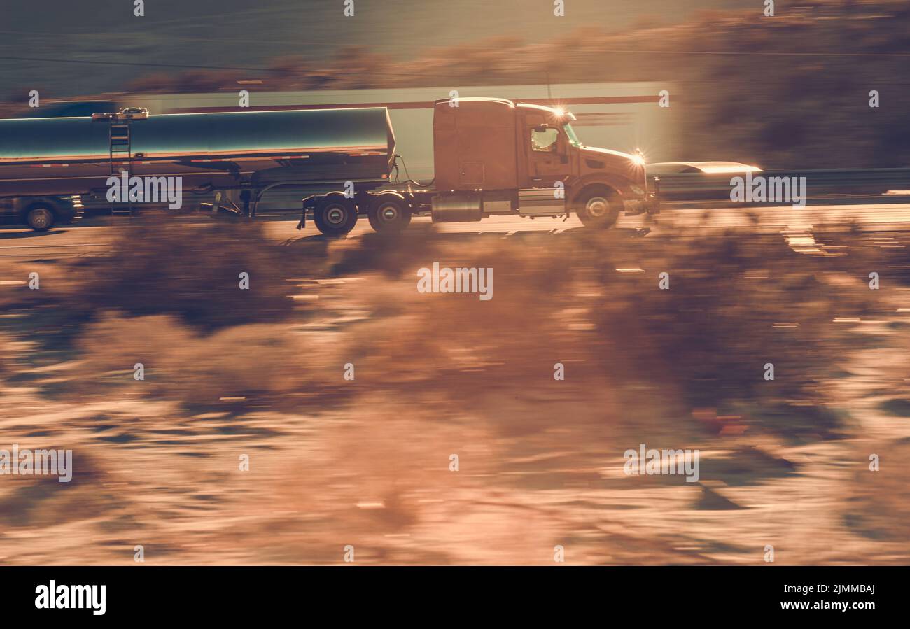 Photo du concept de gros camion-citerne à mouvement rapide entièrement chargé de gaz en descendant la route pour terminer la livraison. Plantes floues le long de la route dans Banque D'Images