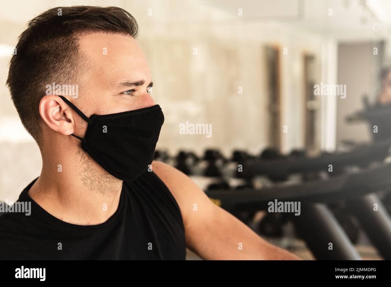 Jeune homme sportif portant un masque de prévention pendant son entraînement en salle de gym Banque D'Images
