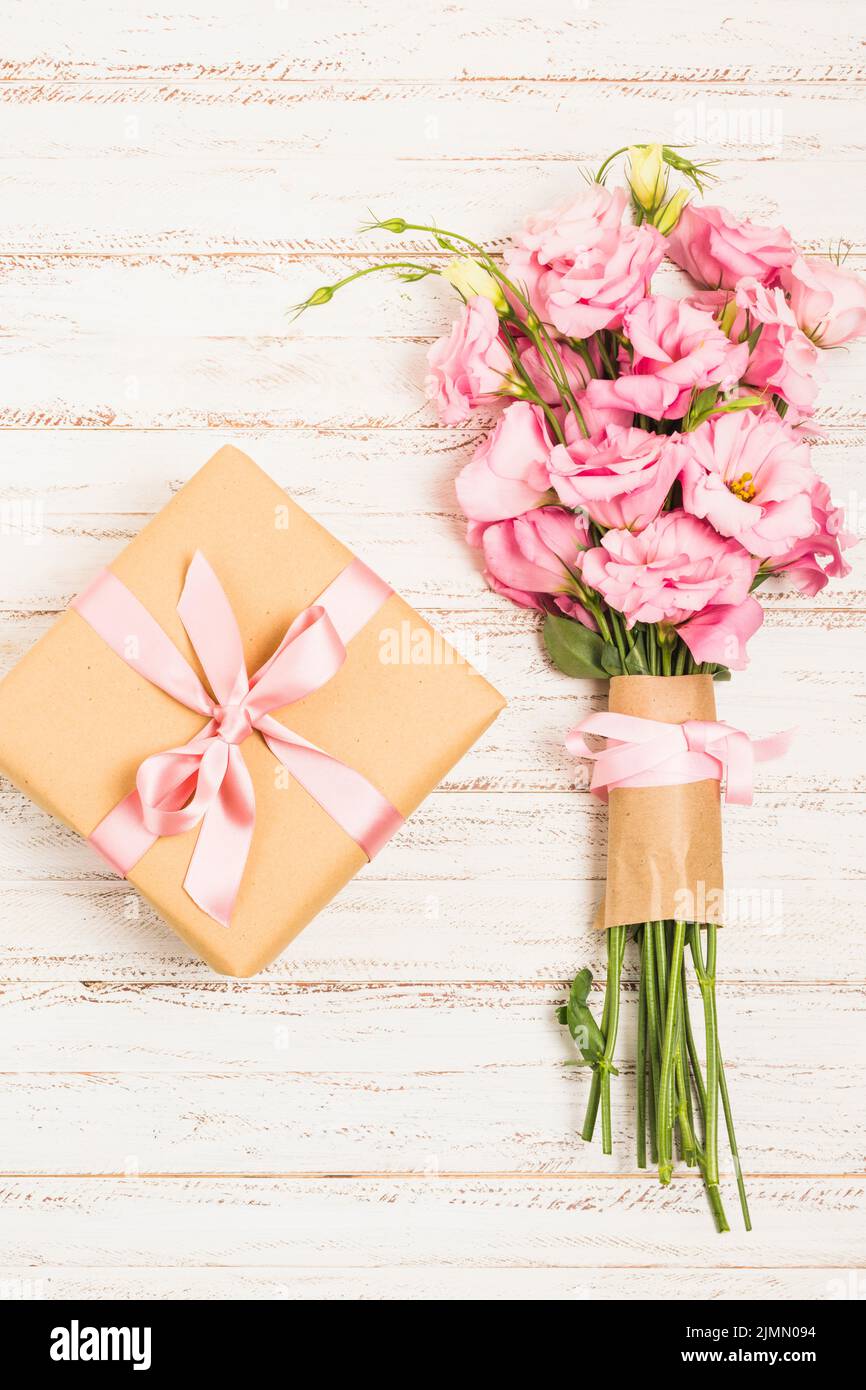 Beau bouquet de fleurs d'eustoma rose frais avec la surface en bois de la boîte actuelle Banque D'Images