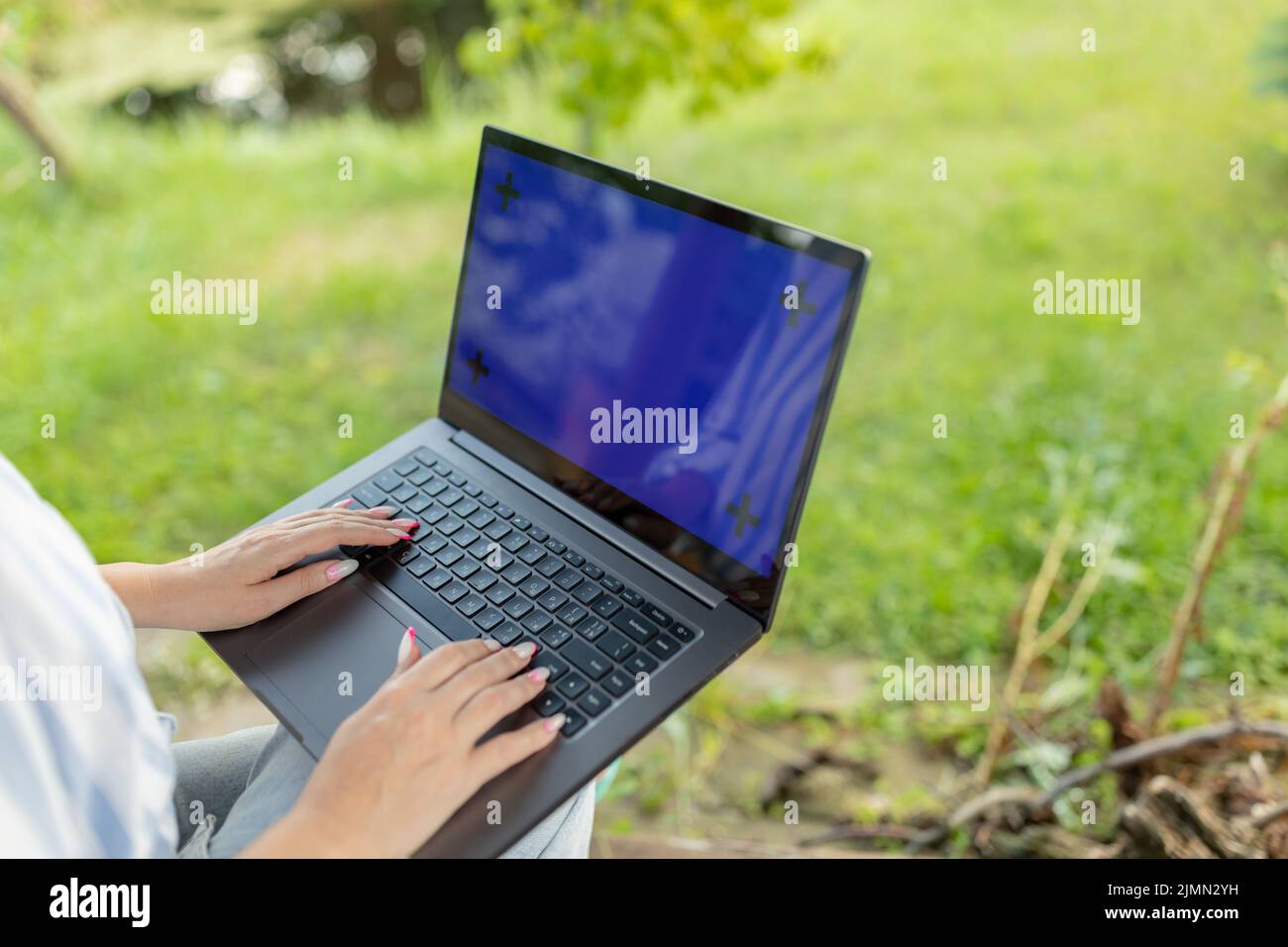 Gros plan image d'une femme travaillant et tapant sur un ordinateur portable clavier dans le jardin Banque D'Images