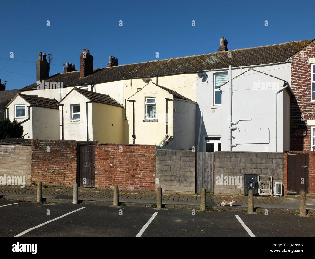 Vue sur l'arrière d'une rangée de petites maisons en terrasse, peintes en blanc et jaune, avec places de parking dans fleetwood lan Banque D'Images