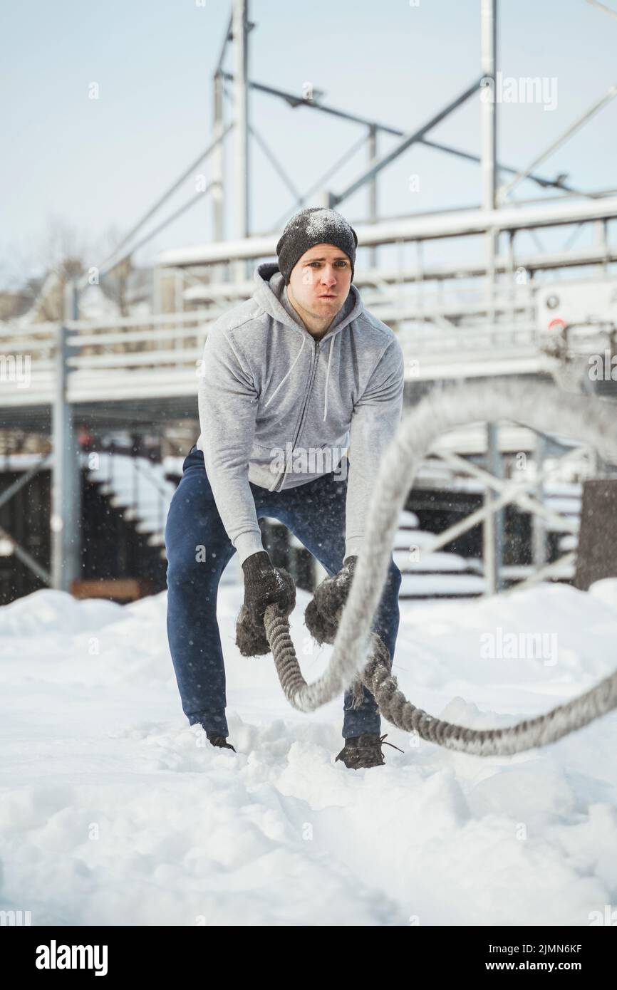 Un jeune athlète s'est sorti avec des cordes de combat pendant la journée hivernale enneigée. Banque D'Images