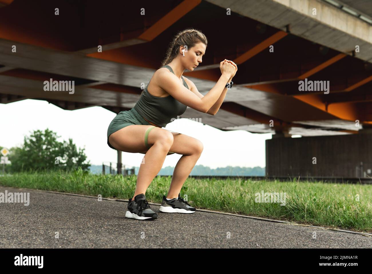 Femme sportive faisant des squats avec un élastique de résistance Banque D'Images