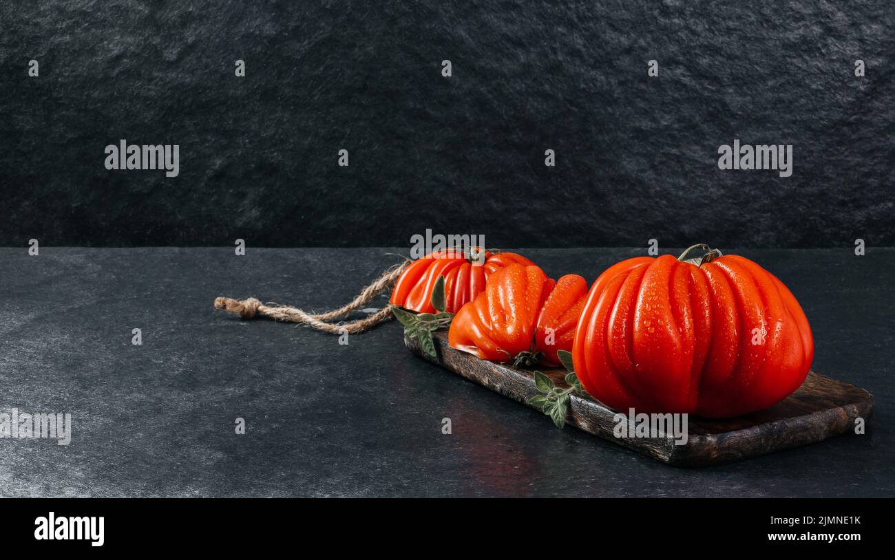 Un groupe de grosses tomates Costoluto avec origan sur fond gris, espace pour le texte Banque D'Images