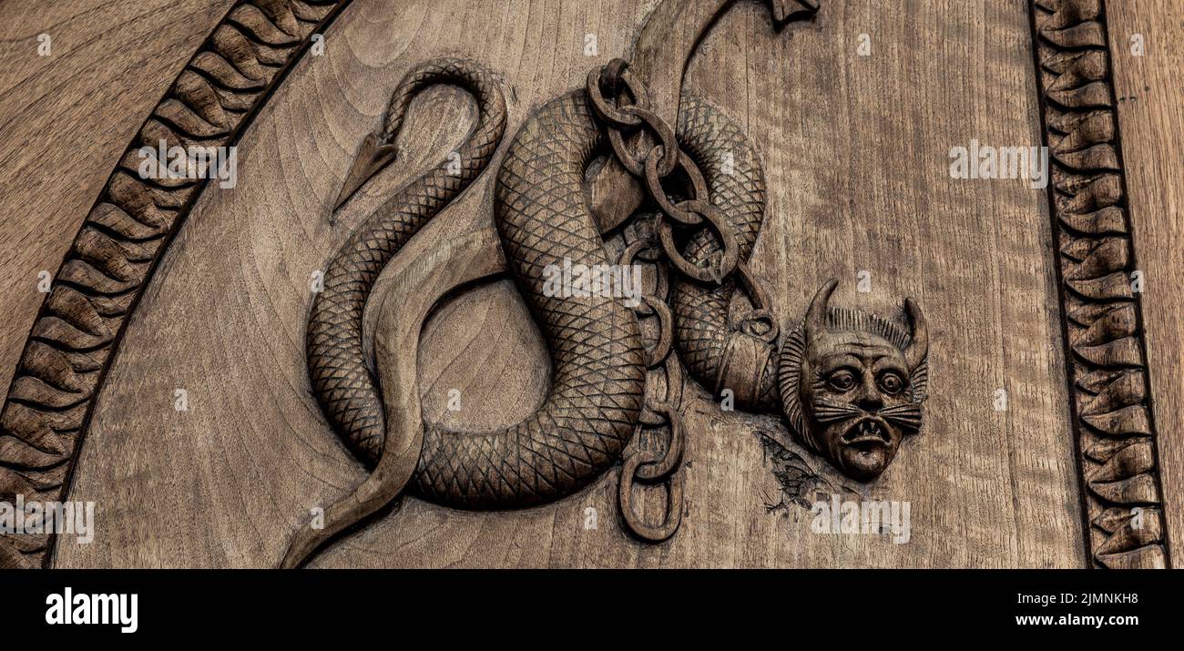Symbole serpent de diable. Créature magique fantaisie sur une vieille porte, abbaye du 12th siècle en Italie. Banque D'Images