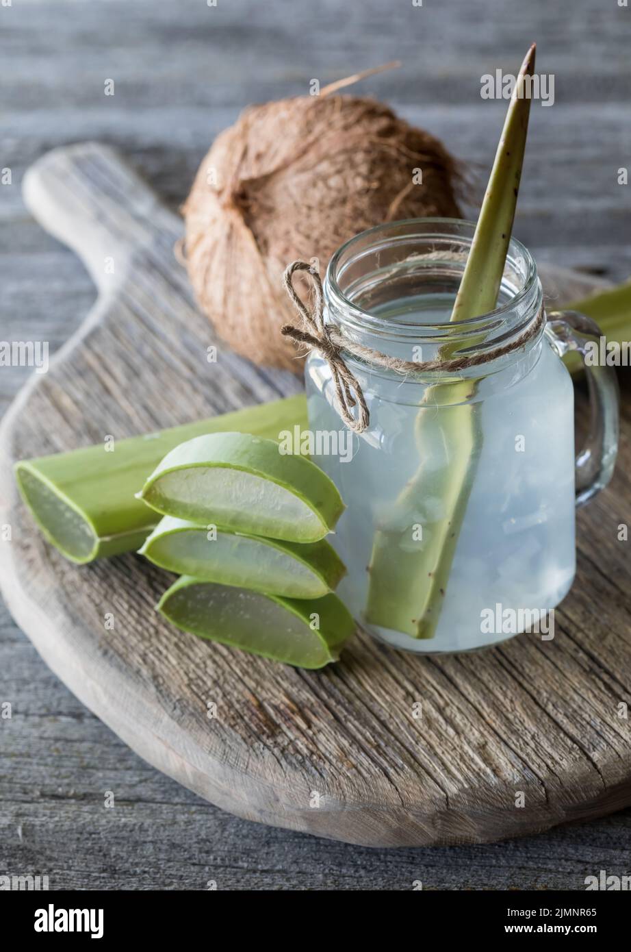 Eau de noix de coco avec des morceaux de vera d'aloès sur un conseil rustique, prêt à boire. Banque D'Images