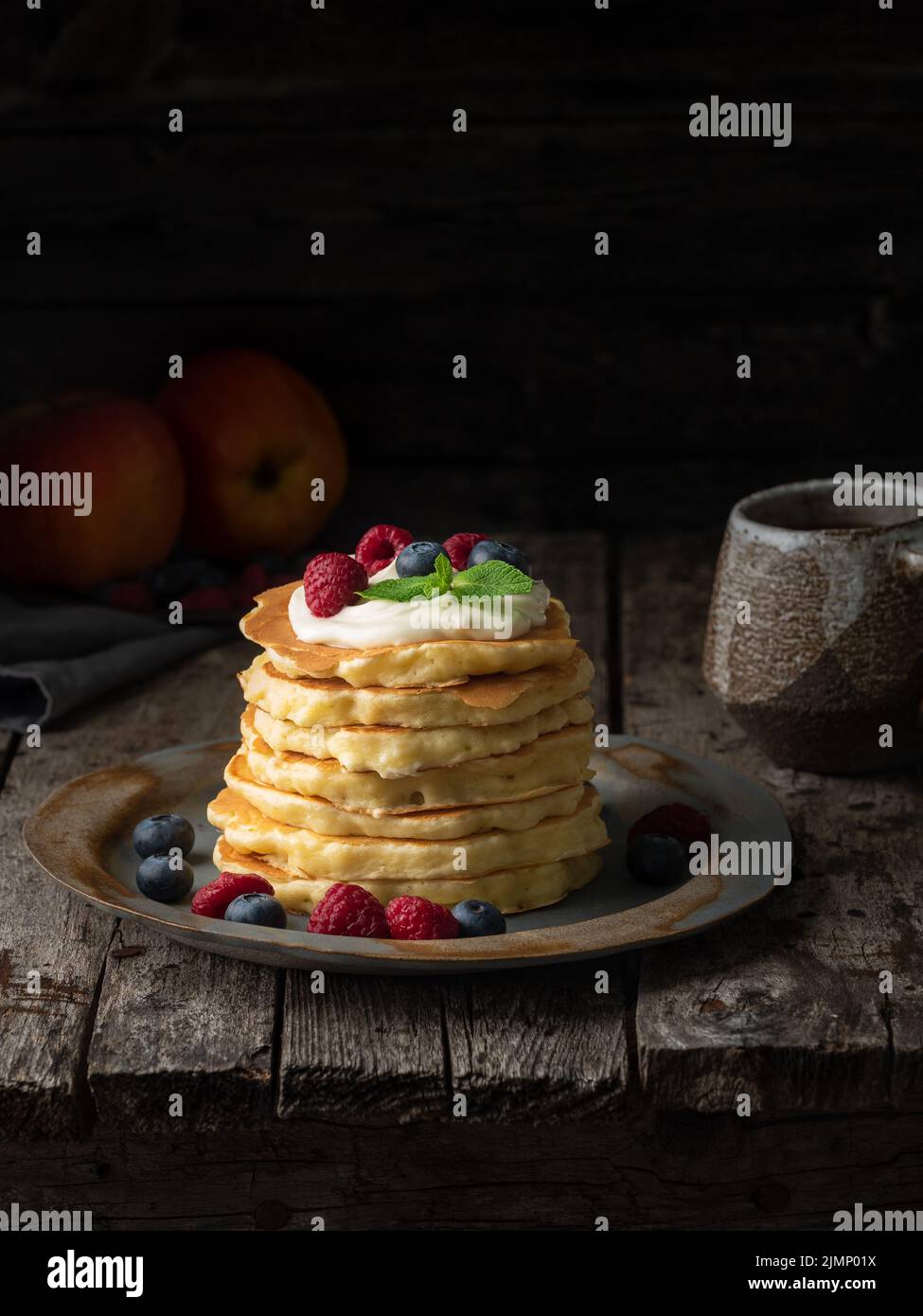 Crêpe à la crème vanille, aux myrtilles et aux framboises. Vue latérale, verticale, espace de copie. Arrière-groun en bois rustique sombre et sombre Banque D'Images