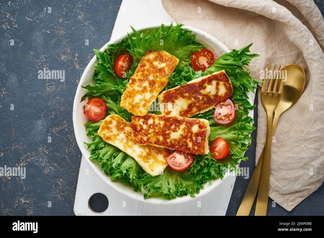 Salade végétalienne avec hallucini frits et tomates, fond sombre, vue sur le dessus Banque D'Images