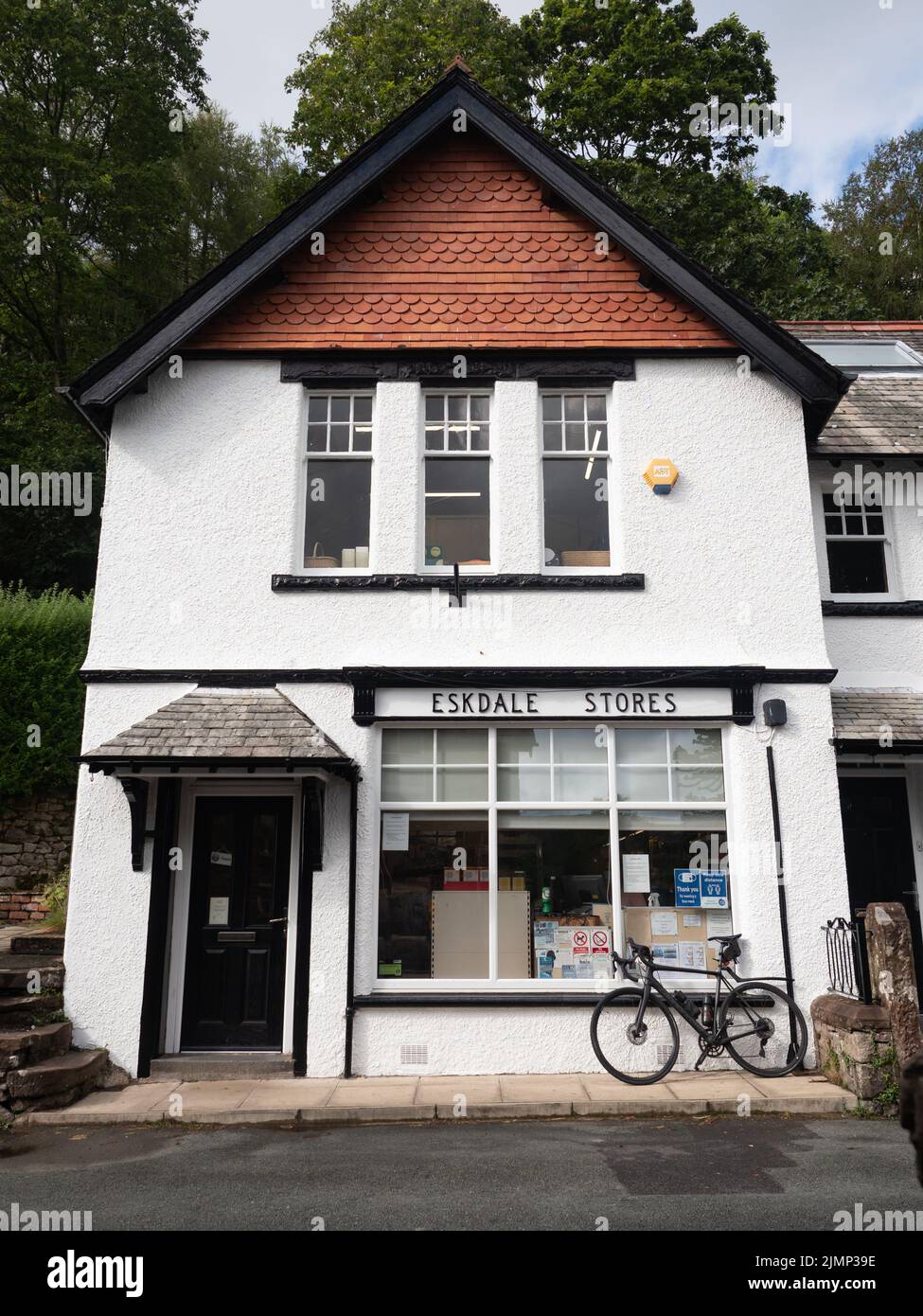 Vélo à l'extérieur des magasins Eskdale, bâtiment noir et blanc, Lake District, Royaume-Uni Banque D'Images