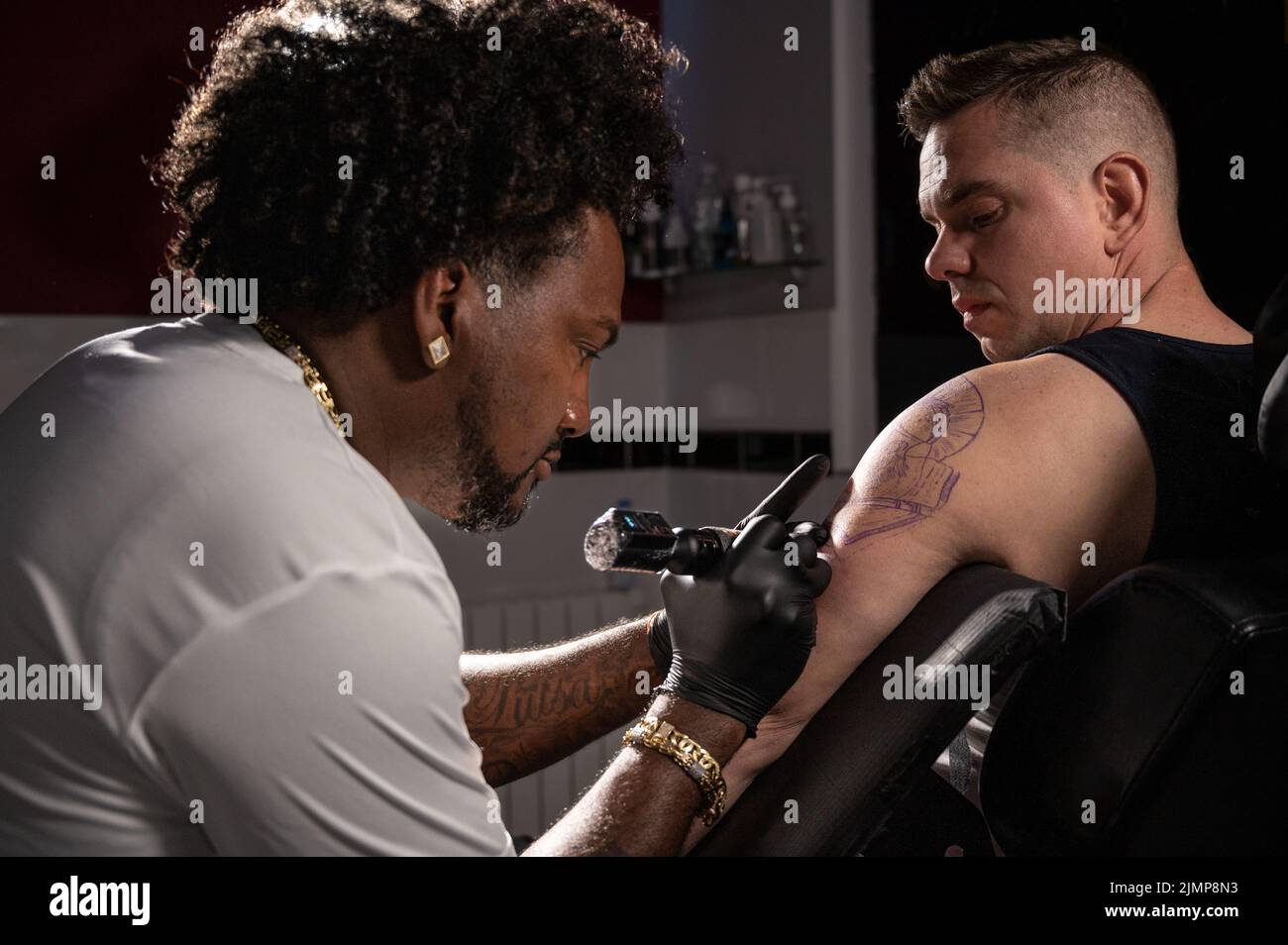 L'artiste professionnel américain de tatouage d'Afrique fait un tatouage sur le bras de client Banque D'Images