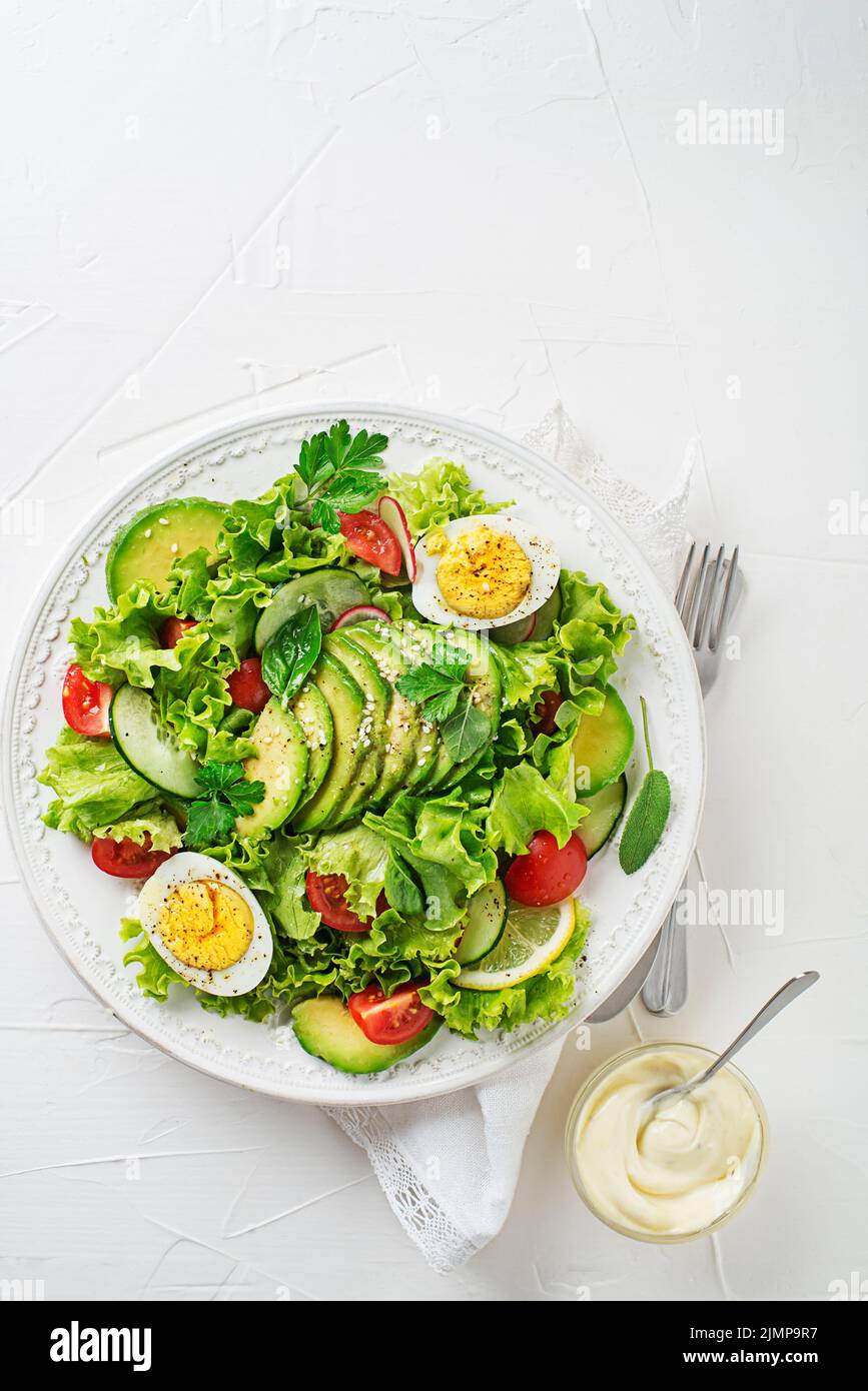 Salade verte mélangée avec avocat, œuf et légumes frais avec sauce crémeuse Banque D'Images