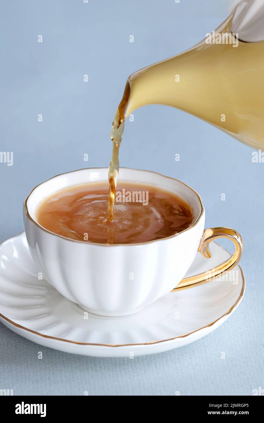 Une boisson fraîche de thé provenant d'une théière anglaise traditionnelle dans une tasse de porcelaine sur une soucoupe. C'est un café fort avec un peu de lait Banque D'Images