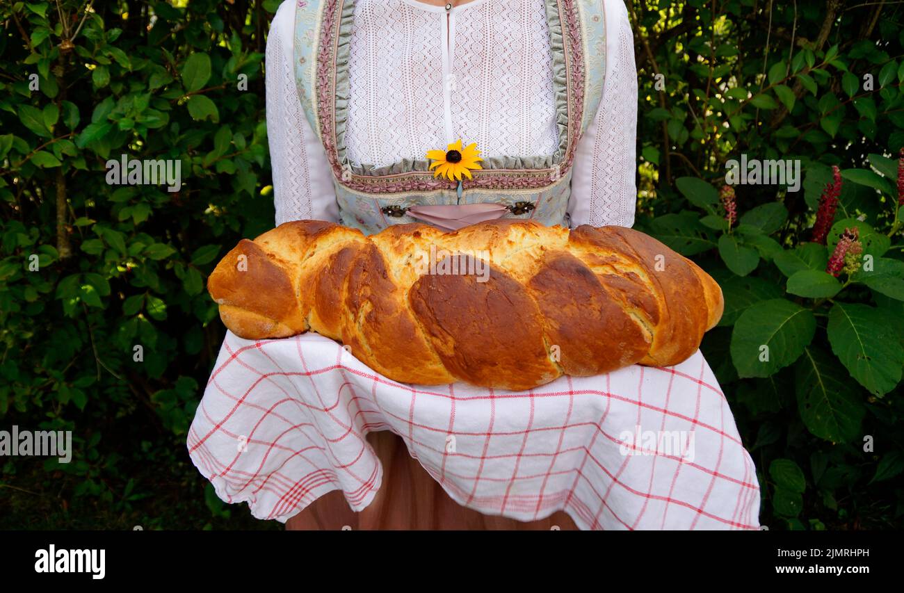 Une femme dans une belle robe traditionnelle bavaroise ou aussi autrichienne dirndl tenant un délicieux pain fraîchement cuit maison de pain allemand rustique appel Banque D'Images