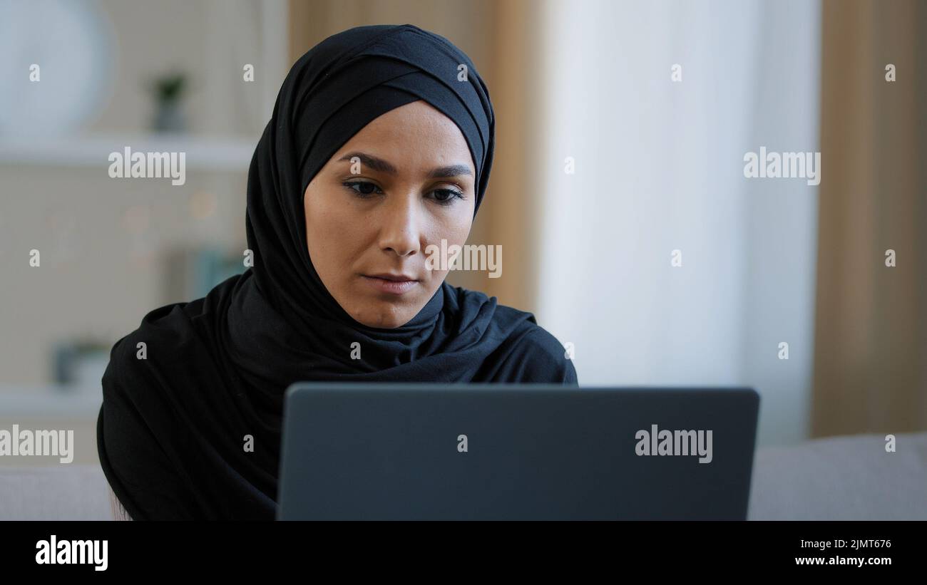 Ciblée ethnique musulmane arabe jeune femme fille islamique étudiante femme d'affaires pigiste assis à la maison travail sur ordinateur en ligne recherche de chat Banque D'Images