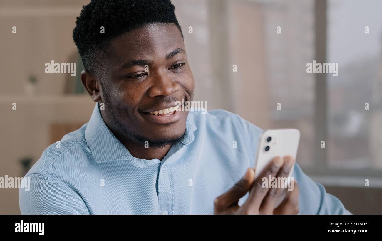Joyeux jeune afro-américain homme d'affaires beau entrepreneur homme travailleur tenir un smartphone parler par vidéo appel salutation ont la réunion virtuelle chat wi Banque D'Images