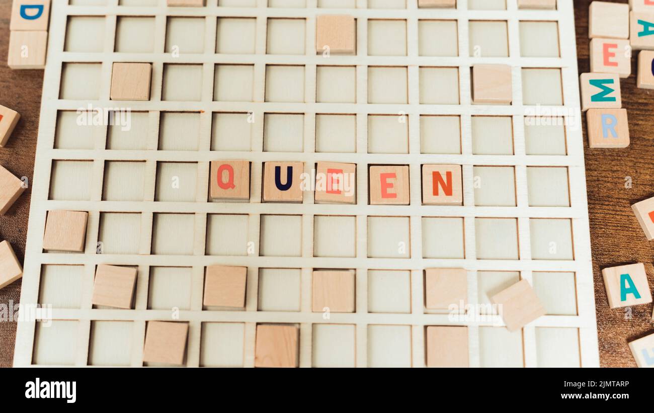 GRAND LIT. Un bloc de bois avec le mot queen écrit avec des lettres rouges, orange et noires. . Photo de haute qualité Banque D'Images