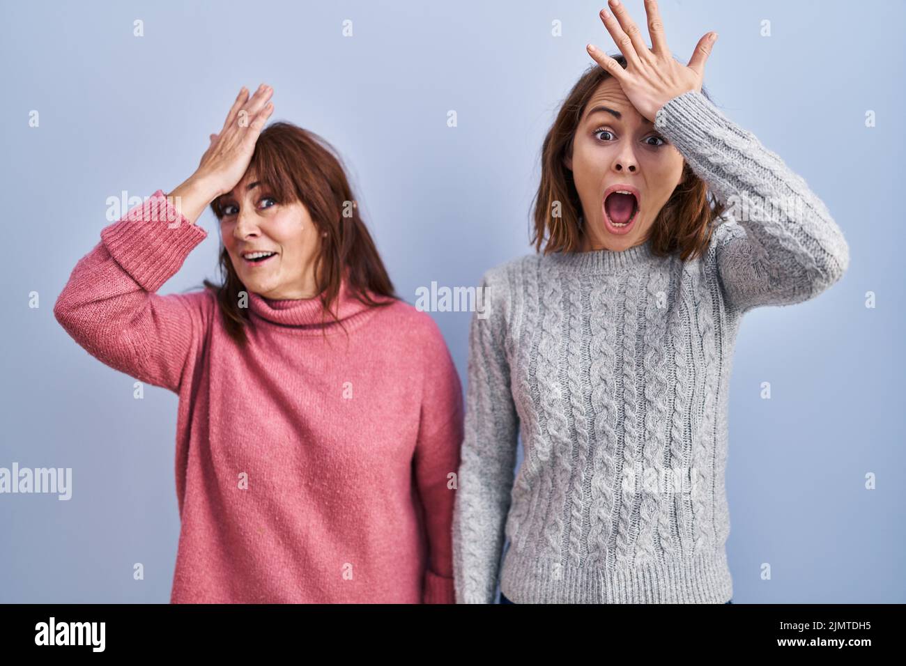 Mère et fille debout sur fond bleu surpris de la main sur la tête pour l'erreur, se souvenir de l'erreur. oublié, mauvais concept de mémoire. Banque D'Images Mère et fille debout sur fond bleu surpris de la main sur la tête pour l'erreur, se souvenir de l'erreur. oublié, mauvais concept de mémoire. Banque D'Images