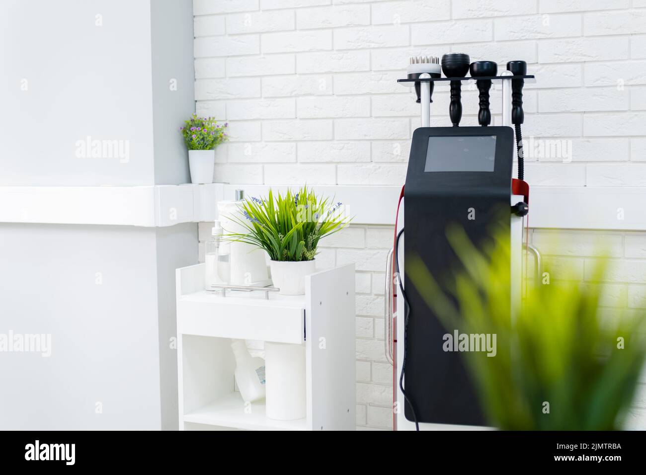 Machine de massage à chaud sous vide amincissant. Massage sous vide des fesses et des jambes. Feuilles vertes au premier plan., Banque D'Images