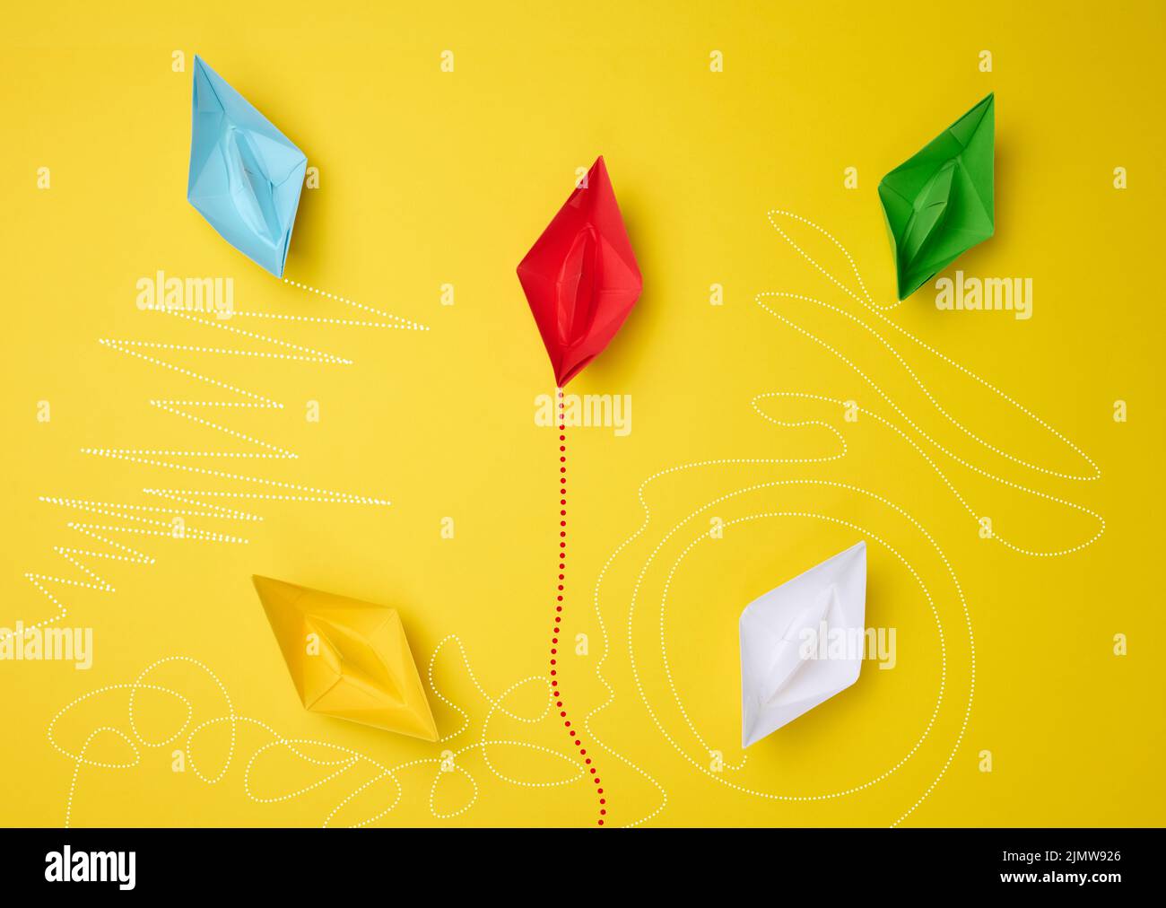 Bateaux en papier avec différentes trajectoires sur fond jaune. Le concept de pensée extraordinaire Banque D'Images