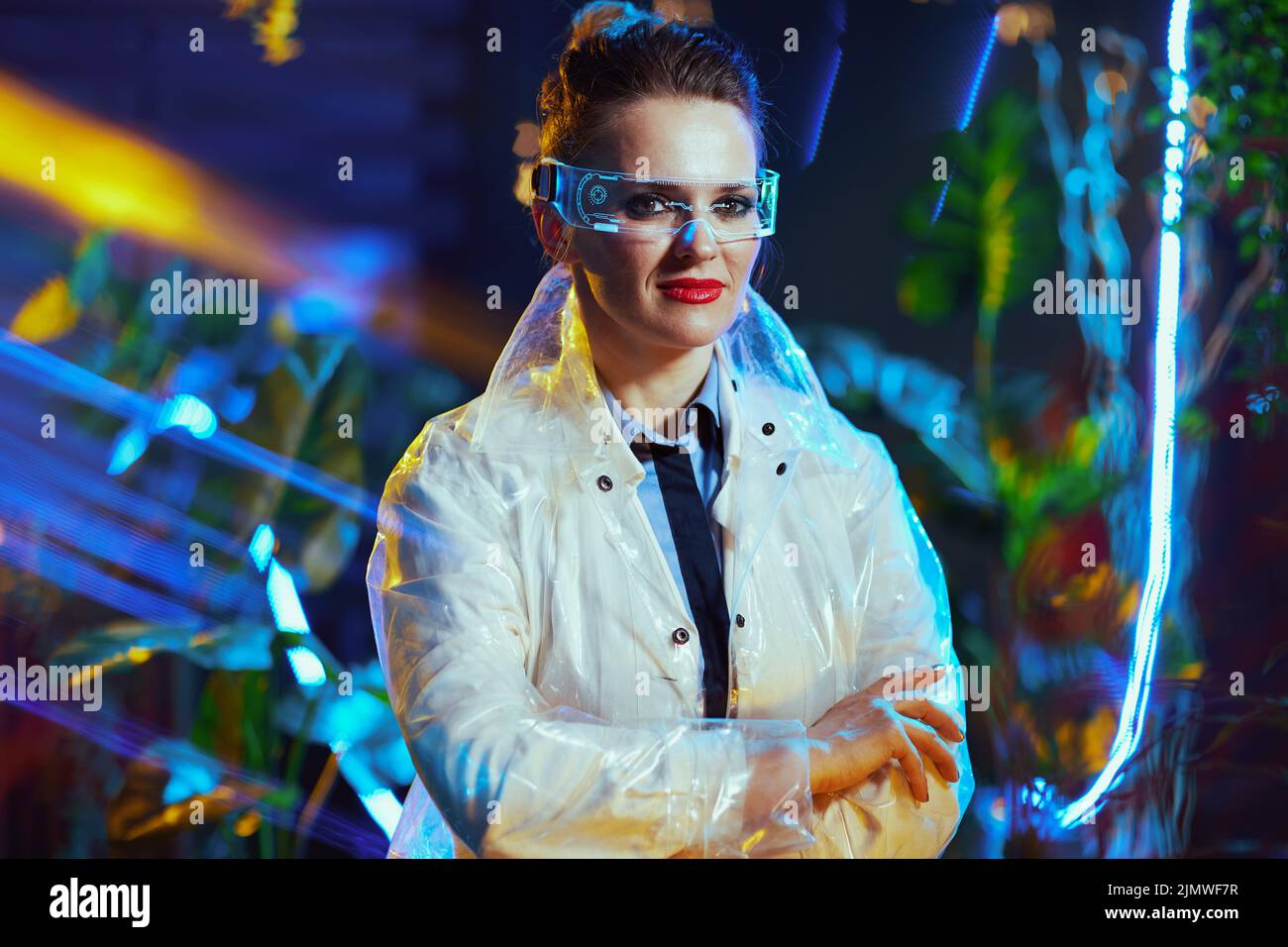 Portrait d'une femme scientifique moderne d'âge moyen heureuse en blouse de laboratoire avec des lunettes futuristes en réalité virtuelle. Banque D'Images