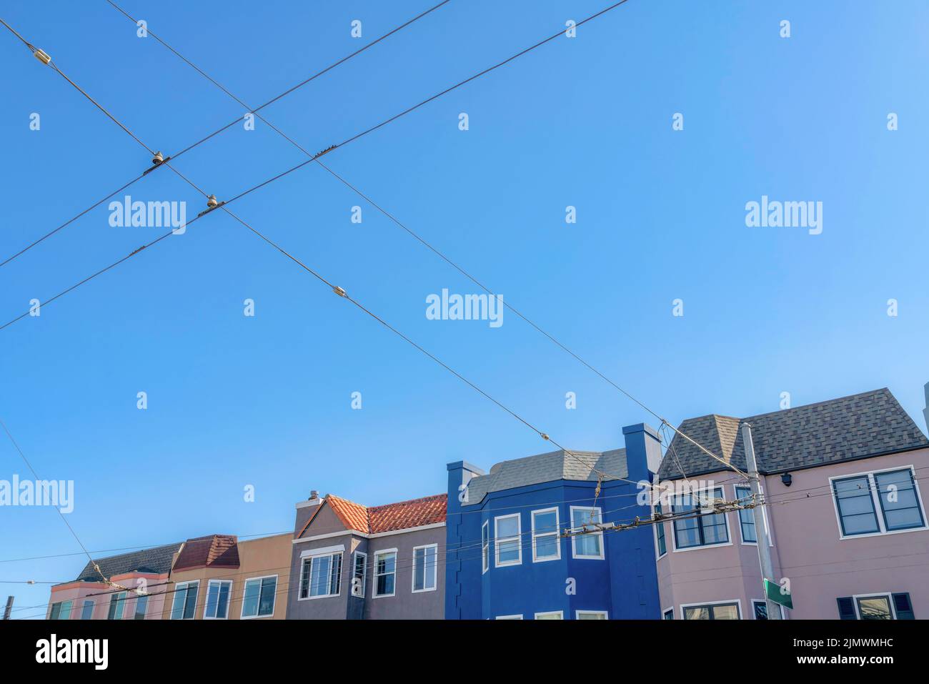 Rangée colorée de maisons à San Francisco, Californie avec vue sur les câbles électriques à l'avant. Il y a une borne électrique à l'avant de la maison Banque D'Images